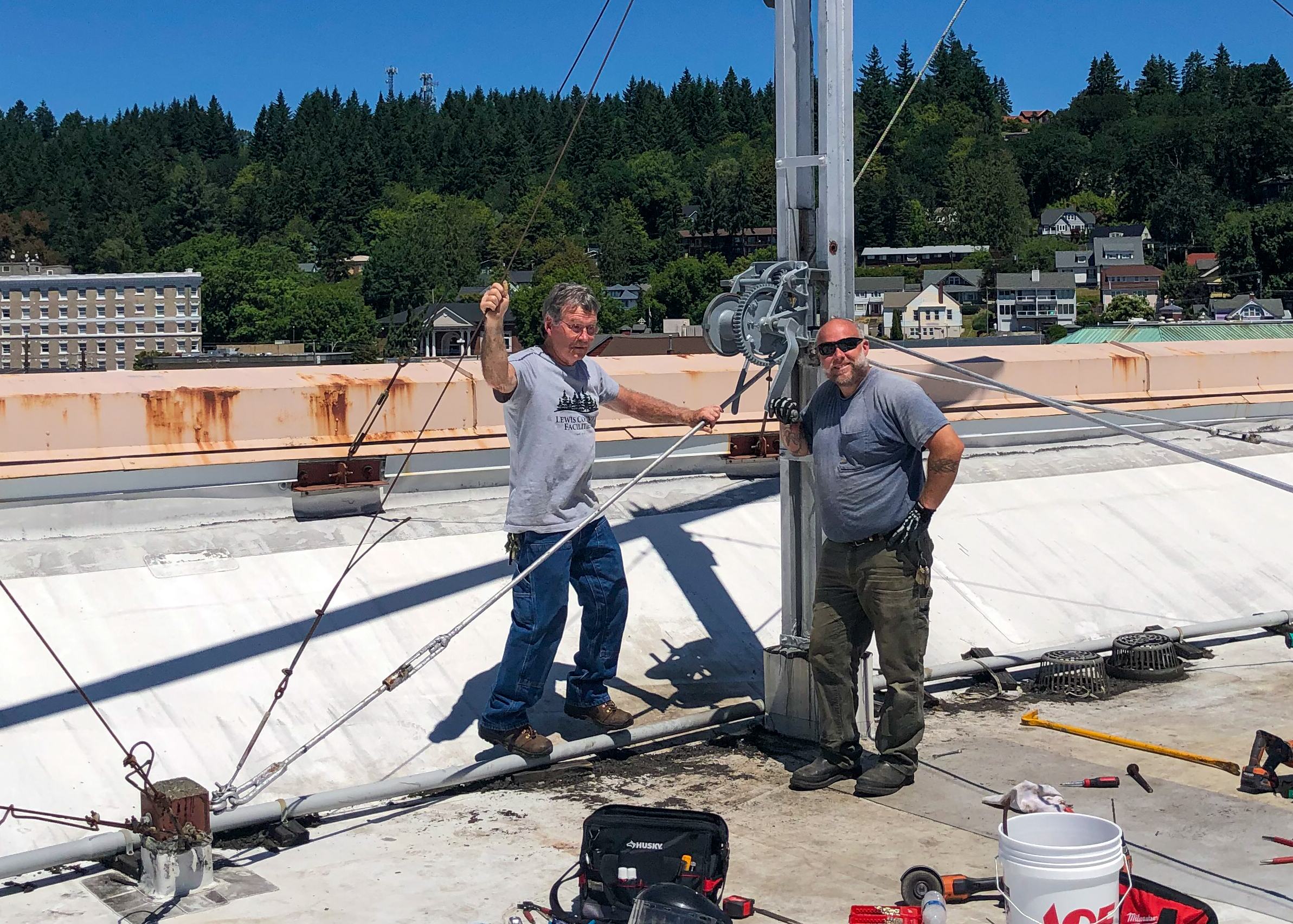 Two Facilities employees working on restoring the flagpole atop the Historic Courthouse.